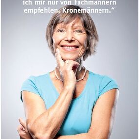 Ältere Frau mit kurzem Haar lächelt, trägt blaues Shirt und Perlenkette, Zitat zu Hörgeräten.