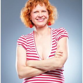 Frau mit roten Locken und gestreiftem Shirt lächelt vor blauem Hintergrund, Hörakustik-Werbung.